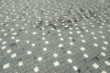 Fototapeta premium street paving stones of gray and white folded with mosaic, dried out after rain