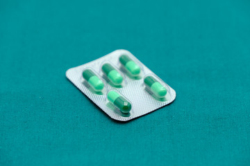 Green drug capsule in medicine panel  isolated on surgical green drape background