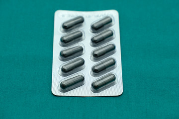 Activated charcoal in medicine panel for diarrhea isolated on surgical green drape background