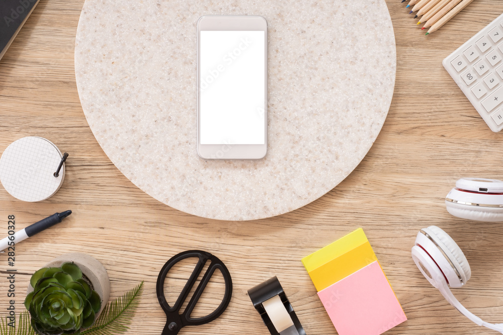 Poster mobile mock up on office desk table top view with stationery,notebook,plant on wooden table background.smart phone screen for display of design.business object flat lay.clipping path device template