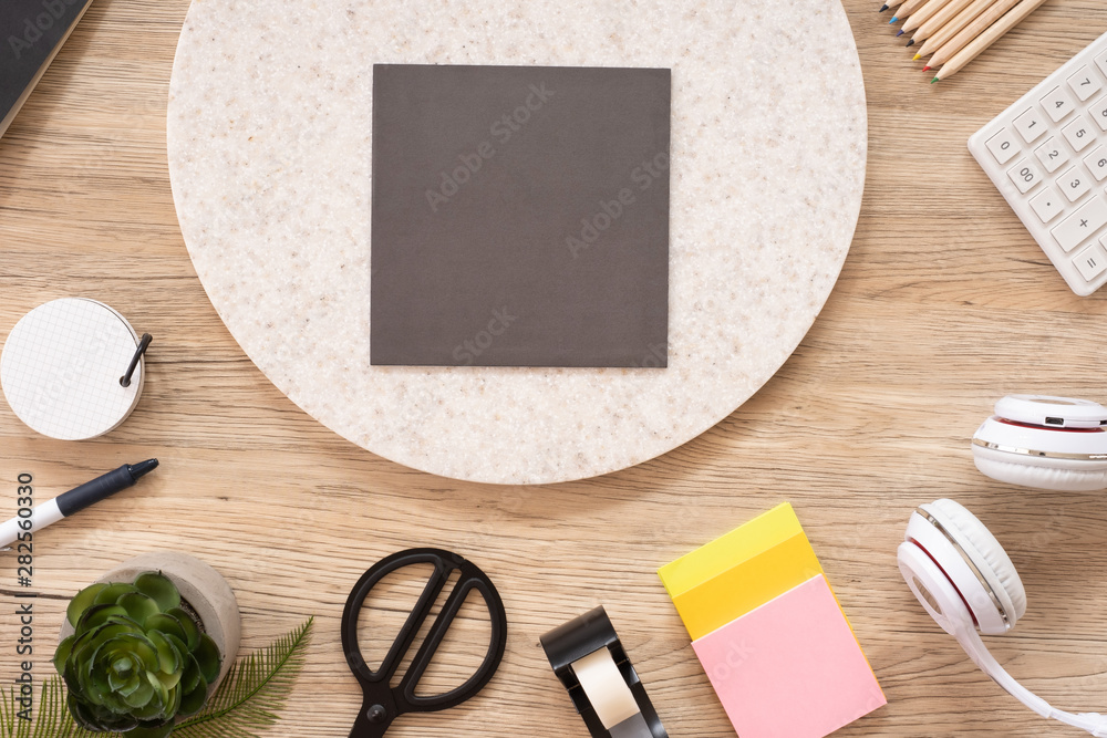 Poster grey poster paper mock up on office desk table top view with stationery,notebook,plant on wooden table background.smart phone screen for display of design.business object flat lay
