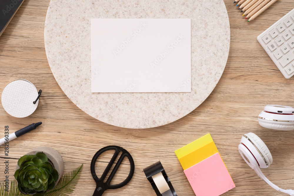 Poster white poster paper mock up on office desk table top view with stationery,notebook,plant on wooden table background.smart phone screen for display of design.business object flat lay