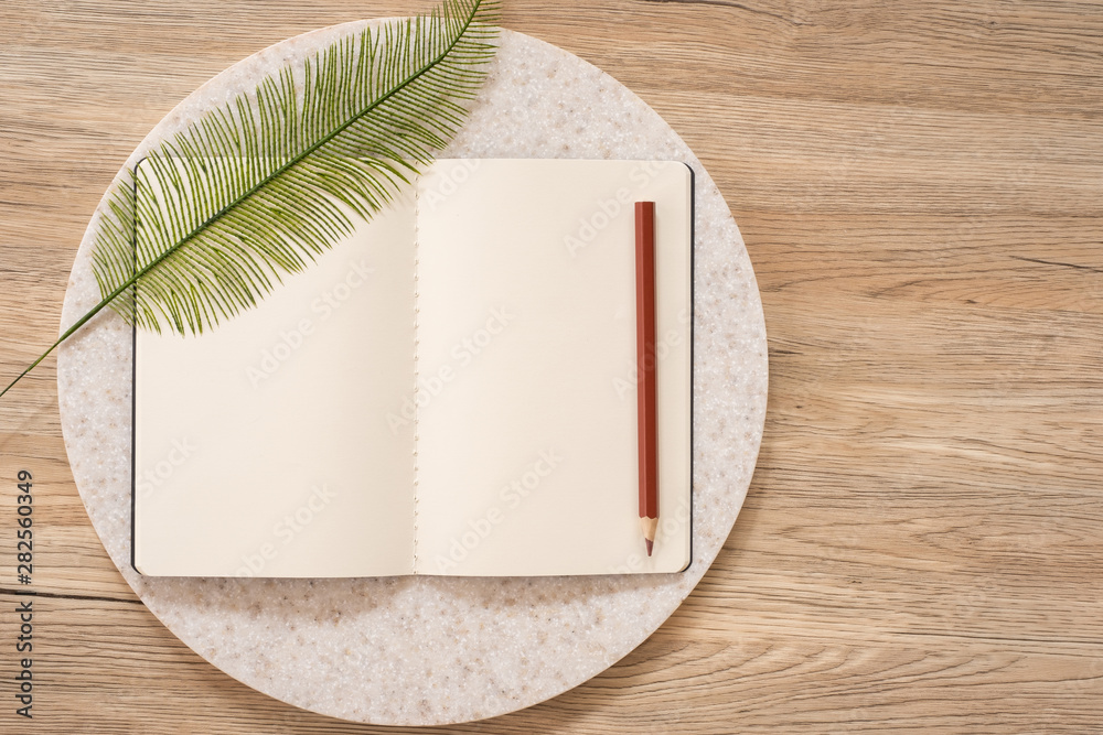 Aufkleber top view of open notebook with leaf and pencil on wooden table with copy space.eco sustainable concept