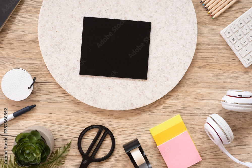 Poster blank blackboard mock up on office desk table top view with stationery,notebook,plant on wooden table background.smart phone screen for display of design.business object flat lay