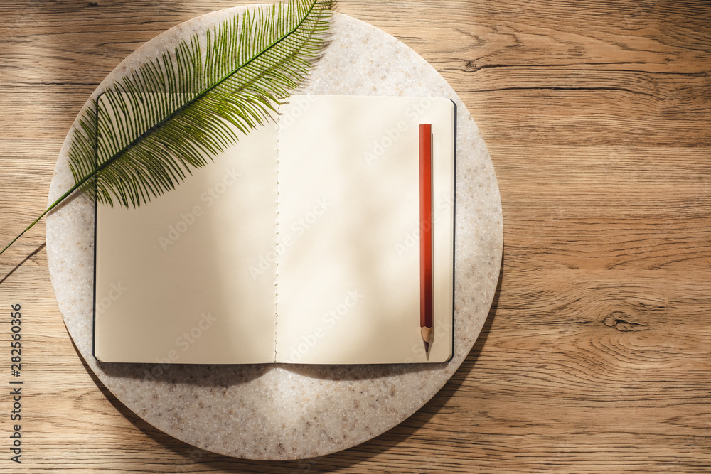 Aufkleber top view of open notebook with leaf and pencil on wooden table with sunlight from window.copy space.eco sustainable concept