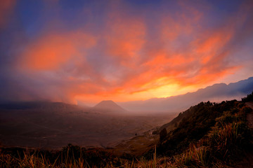 Orange sky glowing at sunset above erupting volcano Mount Bromo one of the best tourist destinations in Java Indonesia