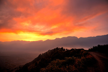 Orange sky glowing at sunset above erupting volcano Mount Bromo one of the best tourist destinations in Java Indonesia