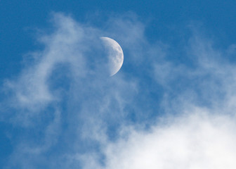 Naklejka na ściany i meble Thin white clouds shroud the half moon as seen in the sky over Tokyo, Japan's capital.