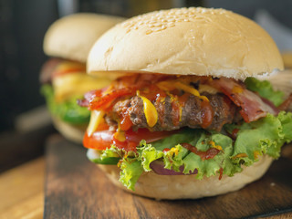 Homemade burgers with beer and cola made of bacon, pork, tomato, lettuce, onion, cheese and spices on wooden background