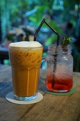 Selective focus of iced milk tea on blurred strawberry italian soda on wooden table in café restaurant, Summer drink, ready to eat, relaxed time, on dark background, Vertical