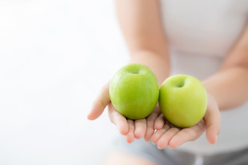 Closeup young asian woman holding and eating green apple fruit in the bedroom at home, lifestyle of nutrition girl healthy and care weight loss, health and wellness concept.