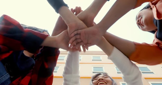 A group of Asian school girls join hands to boom for each other.