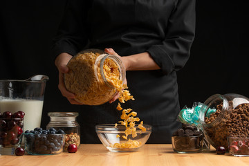 Muesli is poured for preparing breakfast. Healthy and wholesome food, vegetarianism, on a black...