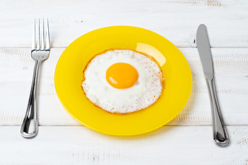fried egg on yellow plate. Fork and knife. Breakfast.