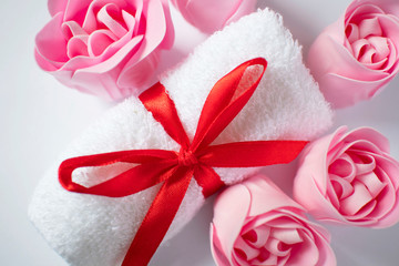 white towel with red bow and rose soap on white background, body care and cleanliness concept
