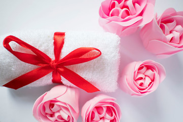 white towel with red bow and rose soap on white background, body care and cleanliness concept