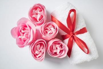 white towel with red bow and rose soap on white background, body care and cleanliness concept