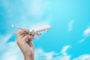 girl hand holding white model plane on blue sky, concept of worldwide travel