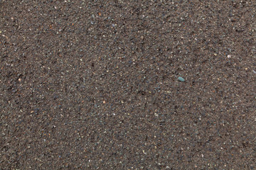 Close-up of sand from the river, mixed with small stones. The texture of gray dark sand, the background.