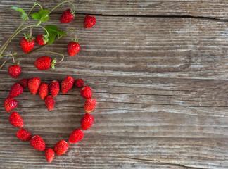 romantic heart lined with strawberries on an old wooden background with copy space