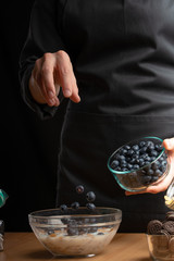 sows morning cereals with fresh berries, blueberries, freezing in motion. Making breakfast cereal, granules, breakfast cereals, cereals, cherry berries, and blueberries. vertical