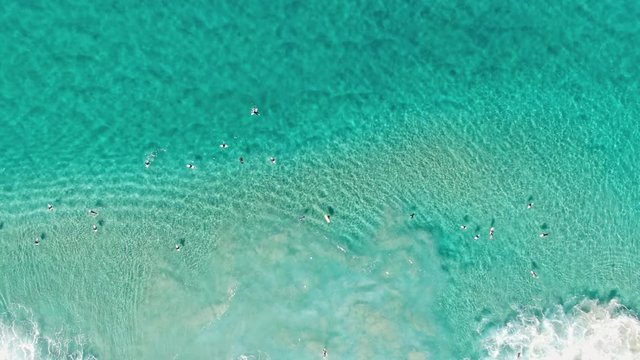 Stunning dynamic 4k aerial bird's eye view of surfers in wetsuits waiting for good waves at world famous Bondi Beach, Sydney, New South Wales, Australia. Turquoise water and beautiful patterns.