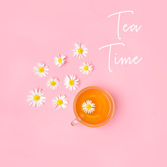 tea time. herbal chamomile tea in a Cup, daisy flowers on pink background. minimalism style. Tea with fresh chamomile flowers, organic healthy beverage.