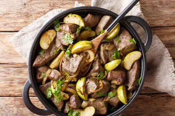 Berlin roasted beef liver with apples and onions close-up in a pan. horizontal top view
