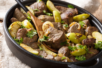 Tasty beef liver with green apples and caramelized onions close-up in a pan. horizontal