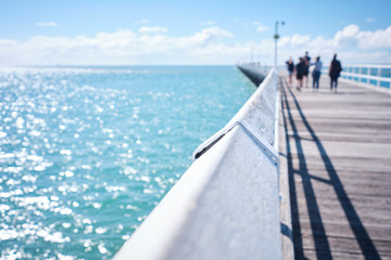 Uranagan Pier Hervey Bay with blue water and blue sky with people walking along it