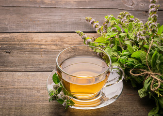 Cup of fresh tea with melissa mint leaves on a wooden rustic background. Healing herbal drink....