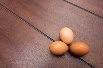 Close up of organic raw chicken eggs in egg box on brown wooden floor background