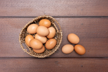 Top view close up of organic raw chicken eggs in basket on brown wooden floor background