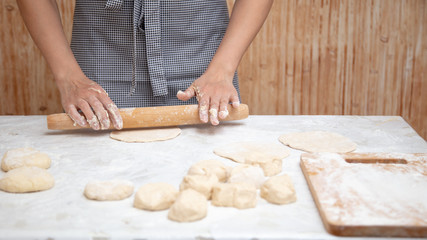 Girl rolls the dough in the kitchen