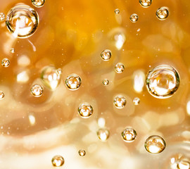 Bubbles of air on the smooth surface of golden water as an abstract background