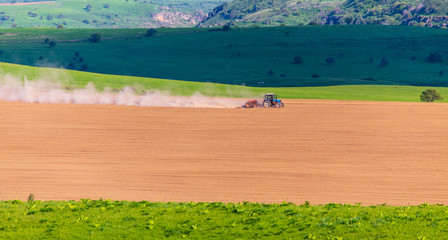 Dust from a tractor working in a field in spring