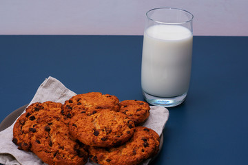 Chocolate breakfast cookies with a glass of milk on a turquoise table