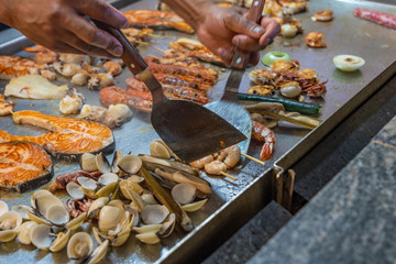 Chef hand frying seafood in buffet restaurant