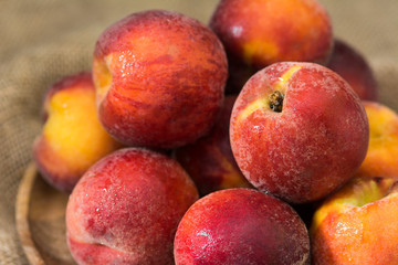 Peaches on a wooden plate on a wooden table. Rustic style