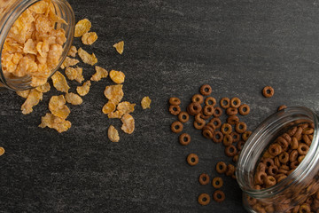 granola and cereals scattered with jars on a dark background, breakfast background