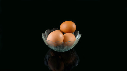 4 four egg inside glass bowl isolated in black with reflection below it
