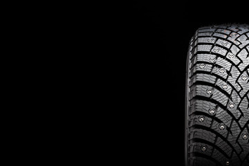 New winter studded tire, safety and premium quality. black background, close-up