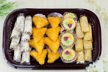 variety of traditional indonesian cake's inside plastic packaging on wood and white brick background