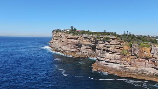 Stunning 4k panoramic aerial drone flight of the Gap, an ocean cliff on the South Head peninsula in the suburb of Watson's Bay in eastern Sydney. The central business district of Sydney in background.
