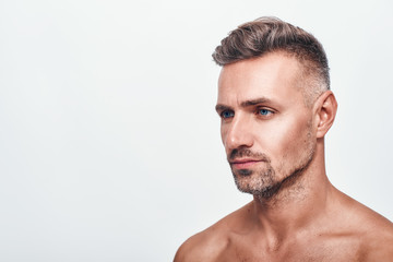 I need to shave. Side view of handsome and sexy man with a stubble looking aside while standing against grey background