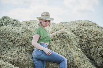 Naklejka na ściany i meble A woman of plus size, American country style, enjoying life, lady with excess weight, stylishly dressed in straw hat denim pants and polka dot shirt. Natural beauty