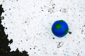 Small ball globe on dirty surface. White paint spilled on the ground. Copy space.