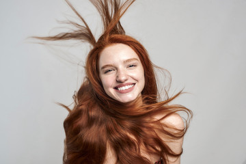 Happy and beautiful Cheerful young woman with tousled red hair looking at camera and smiling while...