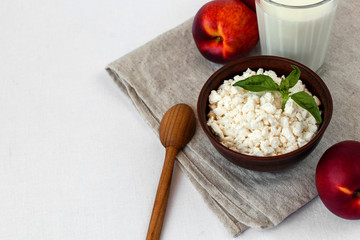 Cottage cheese, peaches, milk and basil on the table. Option serving cottage cheese fresh basil. Rustic style, minimalism. Simple organic food