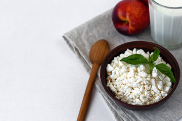 Cottage cheese, peaches, milk and basil on the table with grey tablecloth